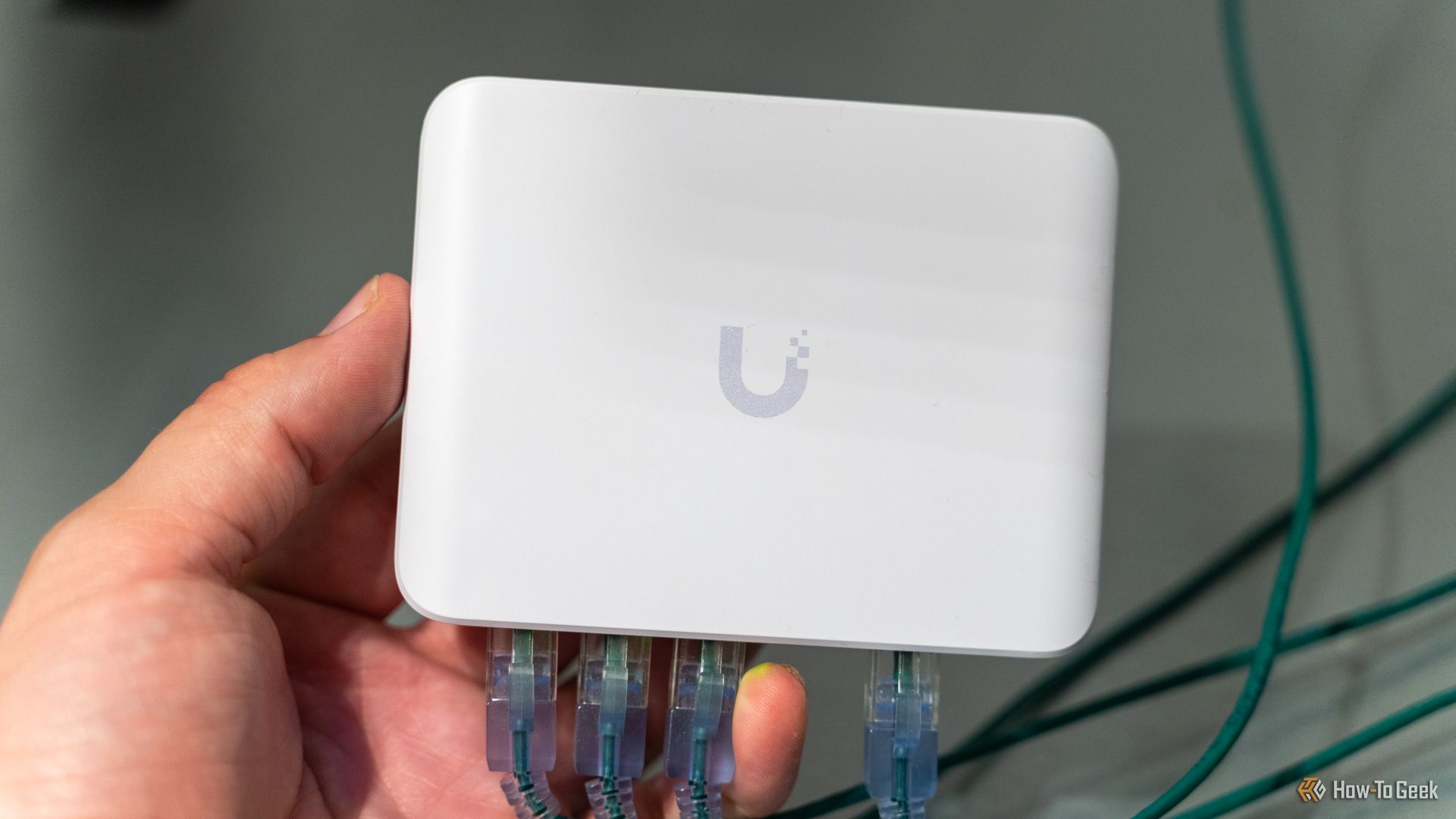 The Unifi Flex Mini 2.5G Ethernet switch with Ethernet cables plugged in being held in a hand.