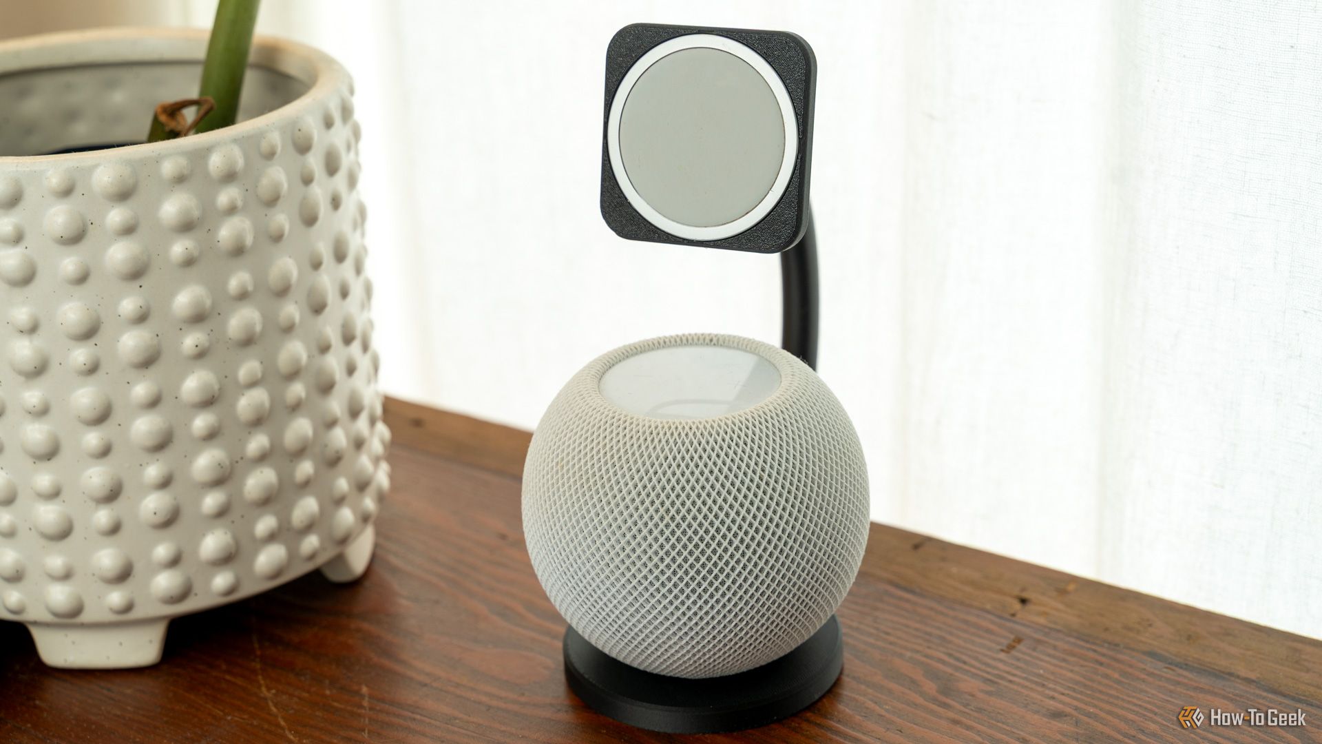 A 3D printed MagSafe dock that also houses a HomePod mini sitting on a wooden table next to a plant.