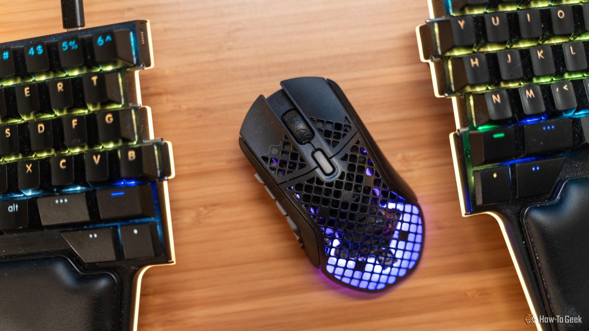 The SteelSeries Aerox 9 wireless MMO gaming mouse between two keyboard halves top down.