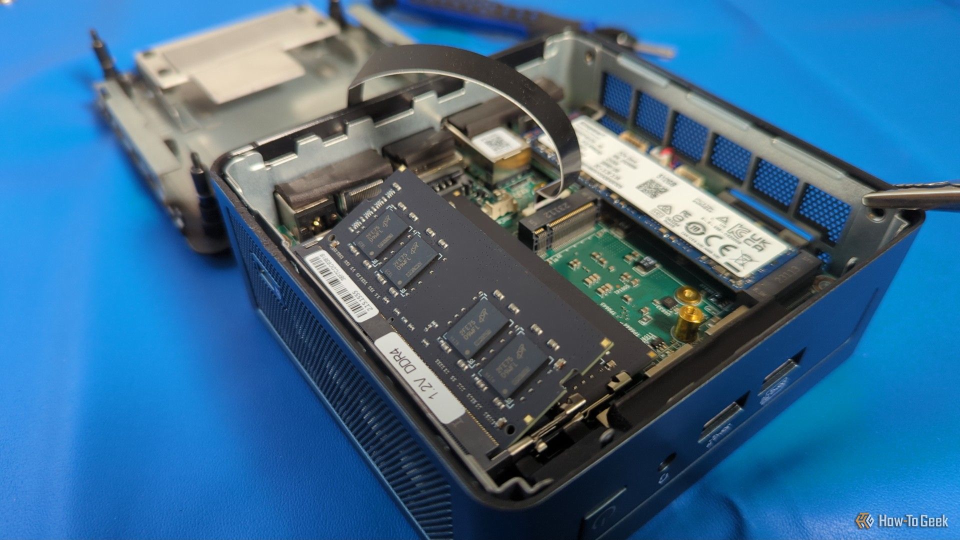 A mini PC open with visible parts and an unnilled ram stick.