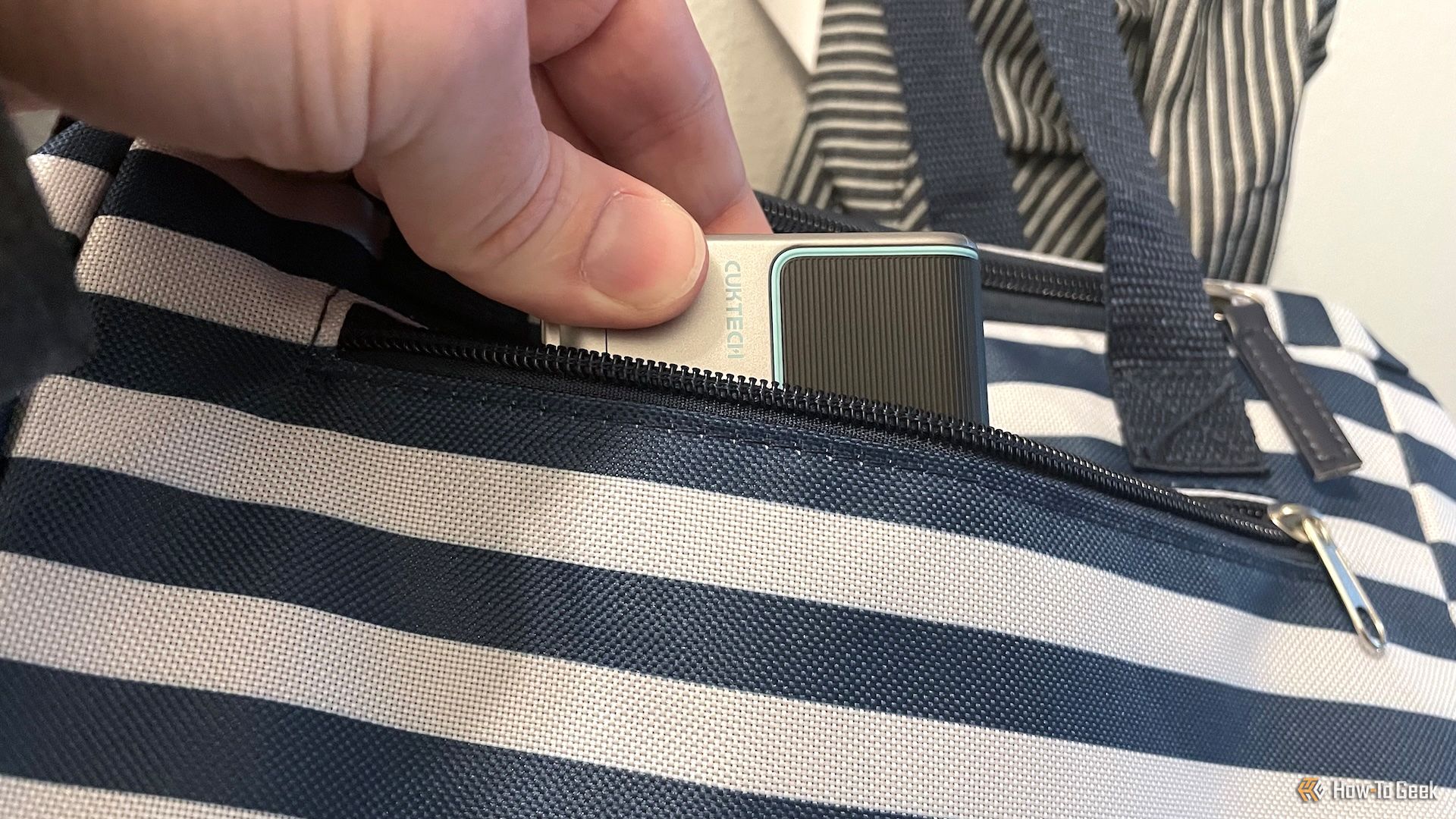 A person putting the CUKTECH 15 GaN Charger 140W in a bag.