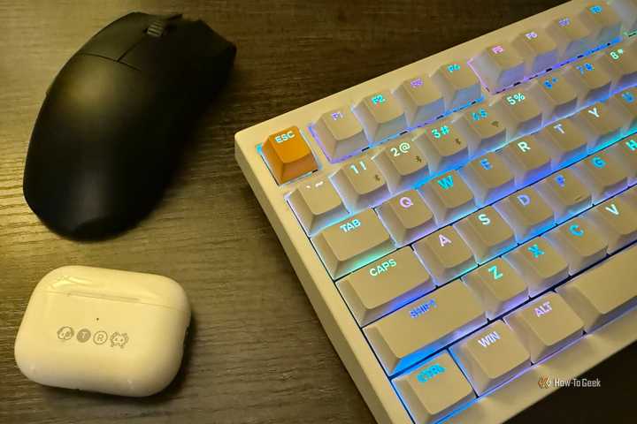 Apple AirPods Pro in an engraved case, a Razer Viper V3 Pro wireless mouse, and a Keychron K2 HE wireless magnetic keyboard on a table.