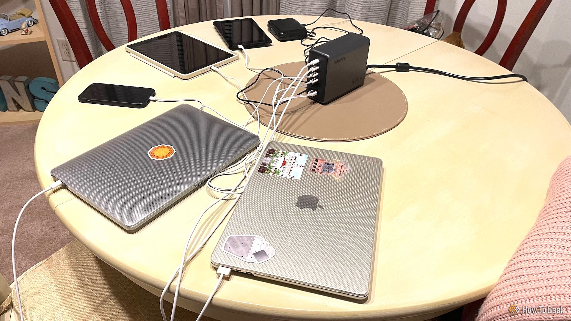 Ugreen Nexode 500W desktop connected to MacBooks, iPhone, iPad, Kindle, and a portable charger.