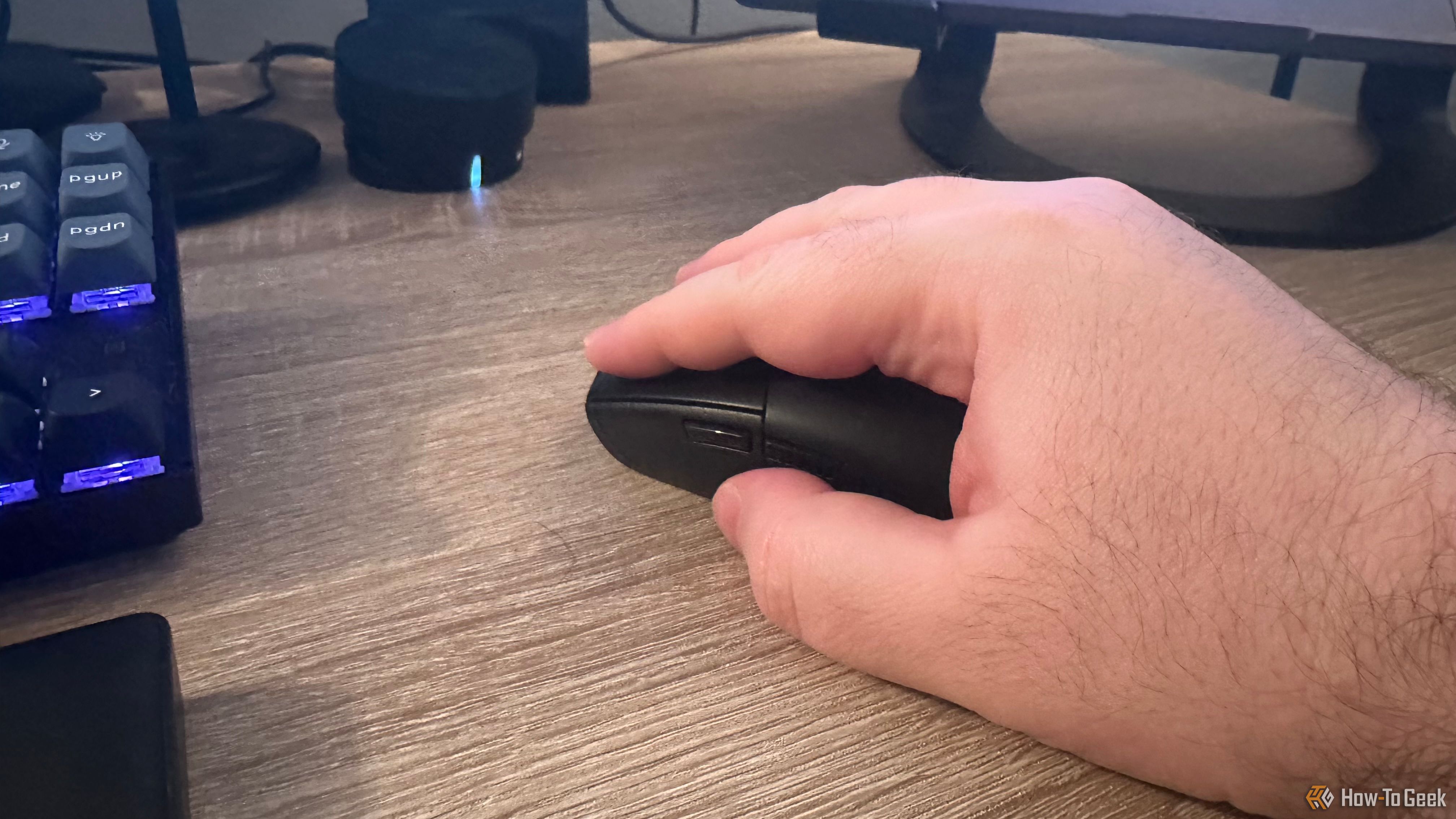 A logitech G305 is held in a large haired hand.