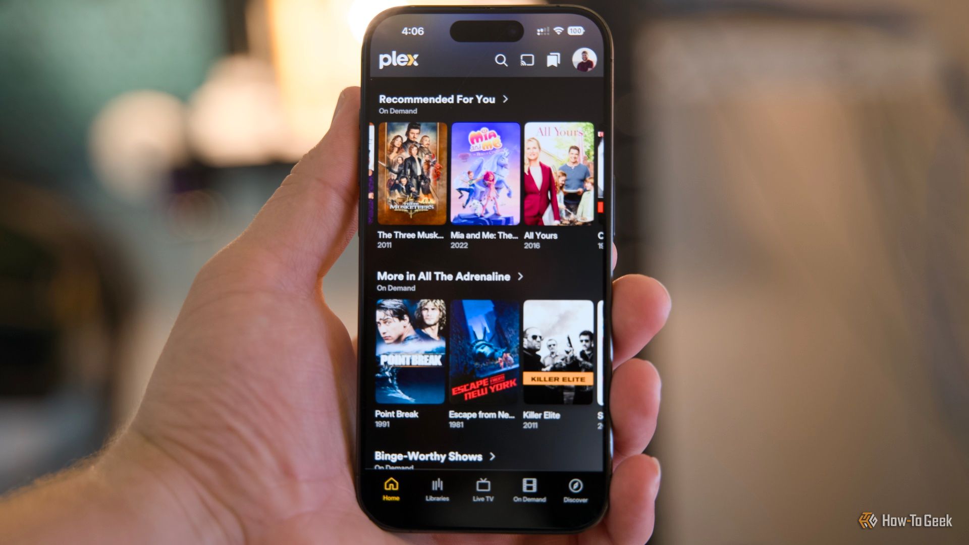 An iPhone 15 Pro in hand showing the Plex recommendations interface.