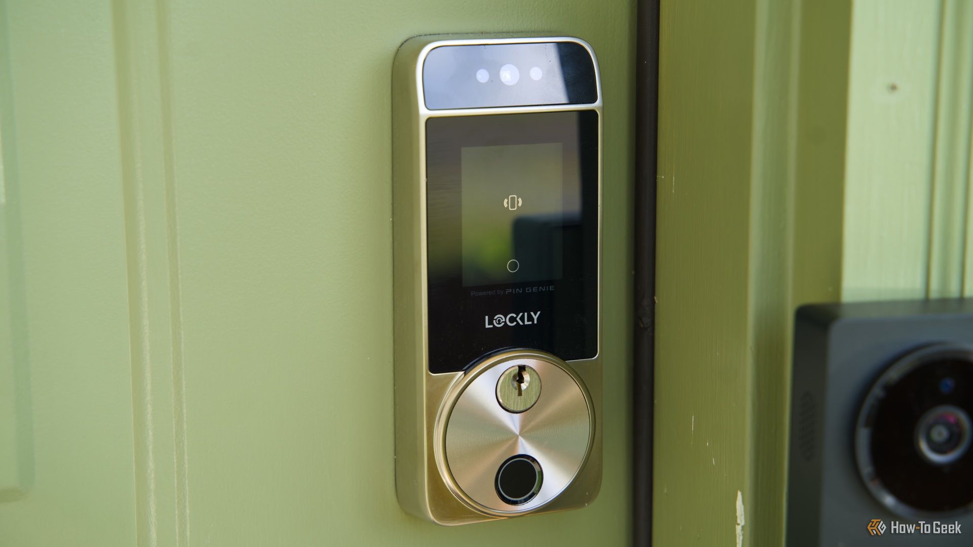 A side view of the Lockly Visage smart lock mounted to a green door.