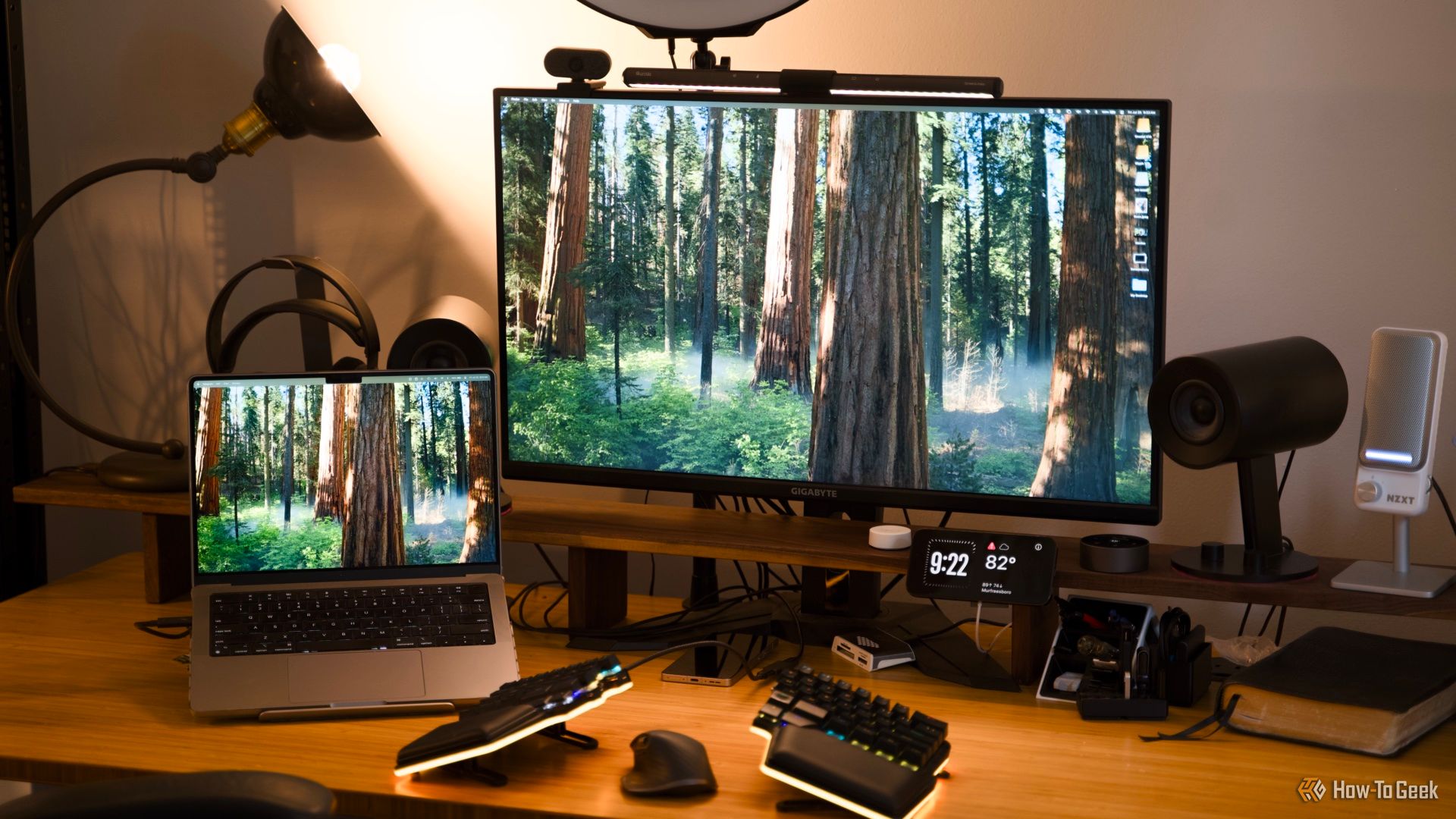 A desk setup featuring a MacBook Pro and a 32-inch 4K monitor with a split keyboard and mouse on the desk.