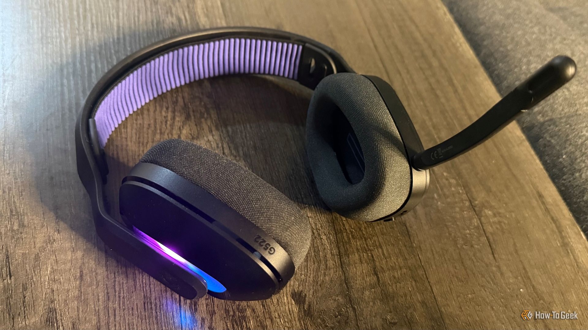 Logitech G522 Lightspeed gaming headset on a table with RGB lighting on and the microphone attached.