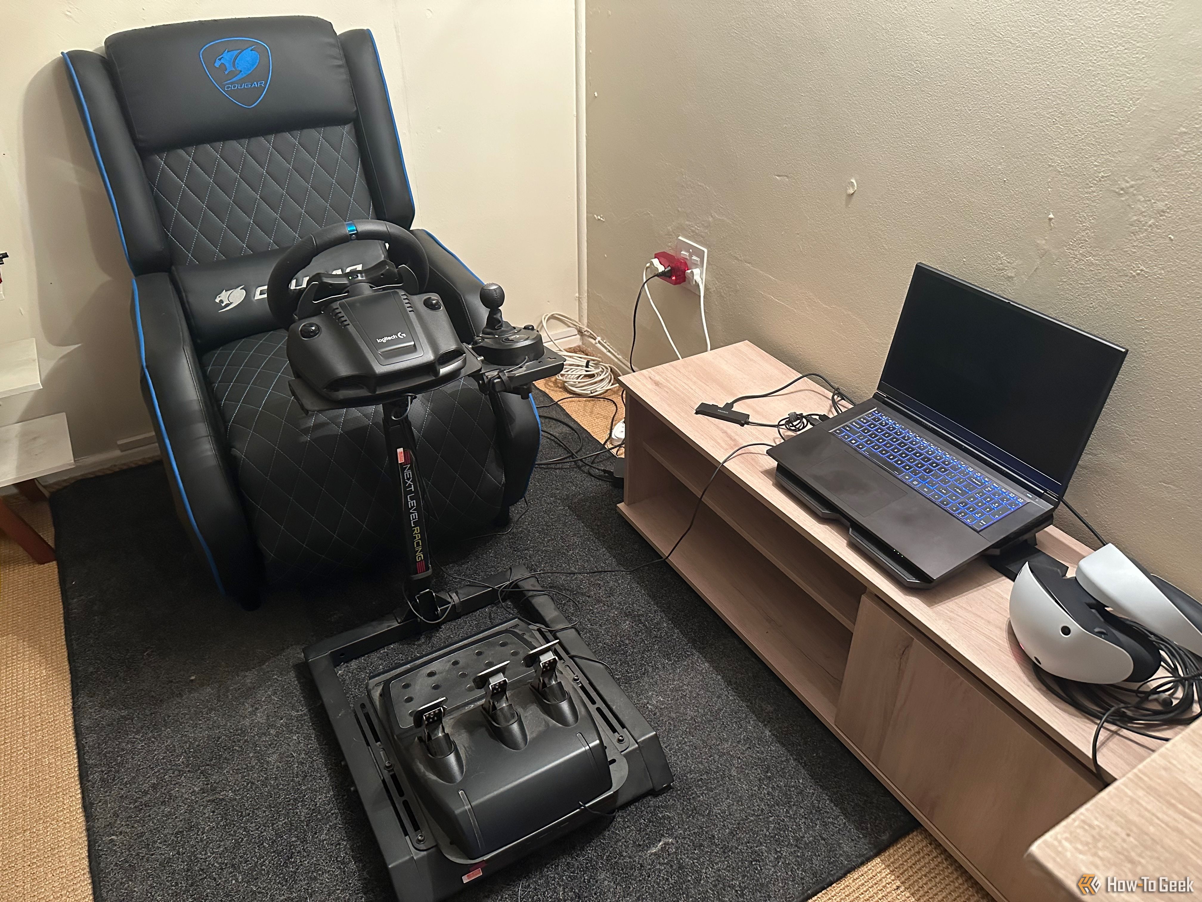 A Logitech G29 next to a laptop and VR headset.