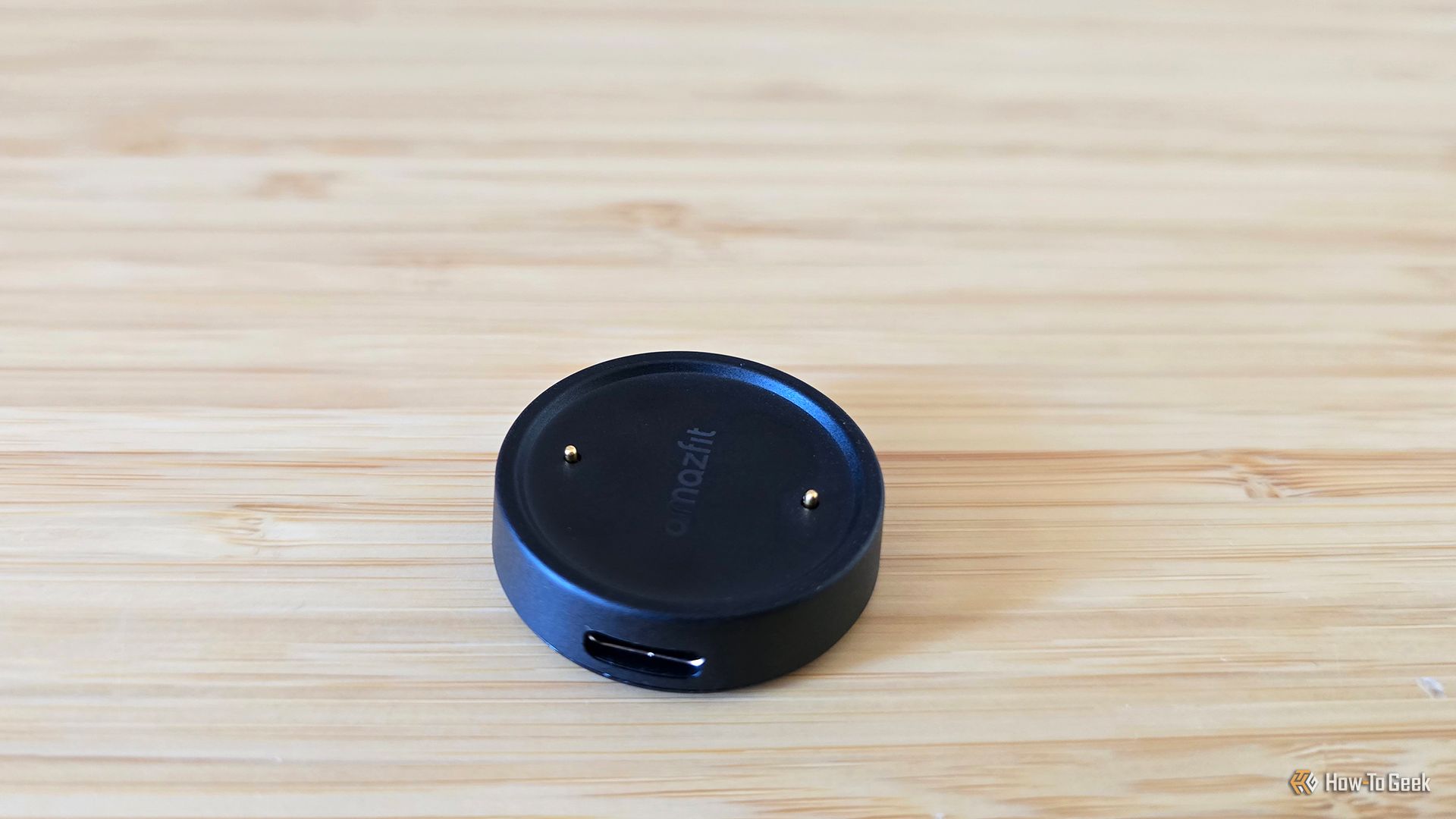 The Amazfit Bip 6 smartwatch's charger sitting on a desk.