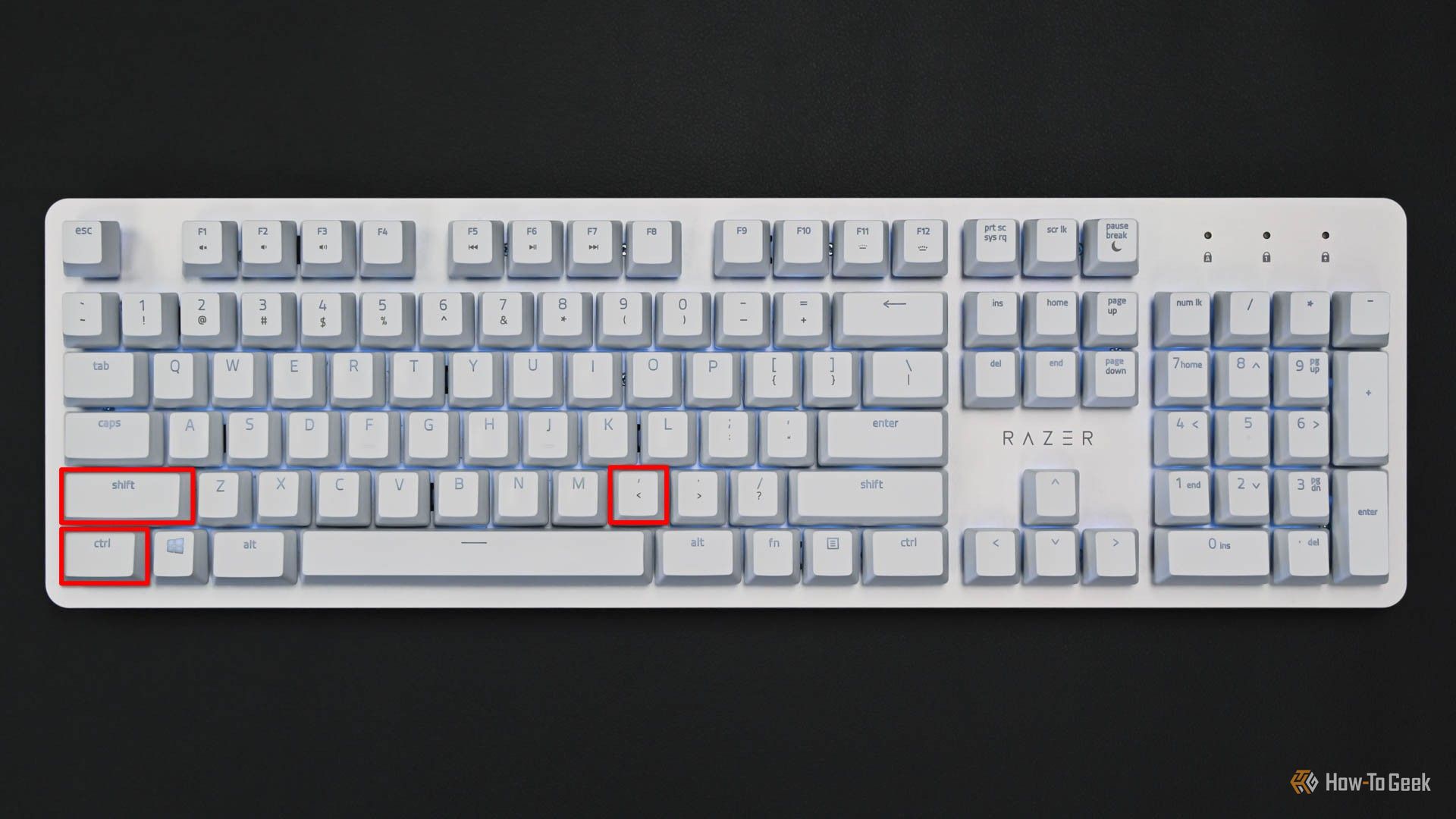 Белая клавиатура с выделенными клавишами Ctrl, Shift и запятая.