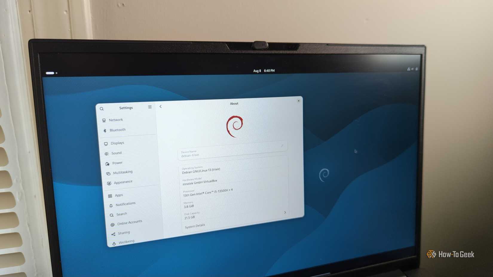 A laptop screen with Debian 13 and the Gnome desktop visible.