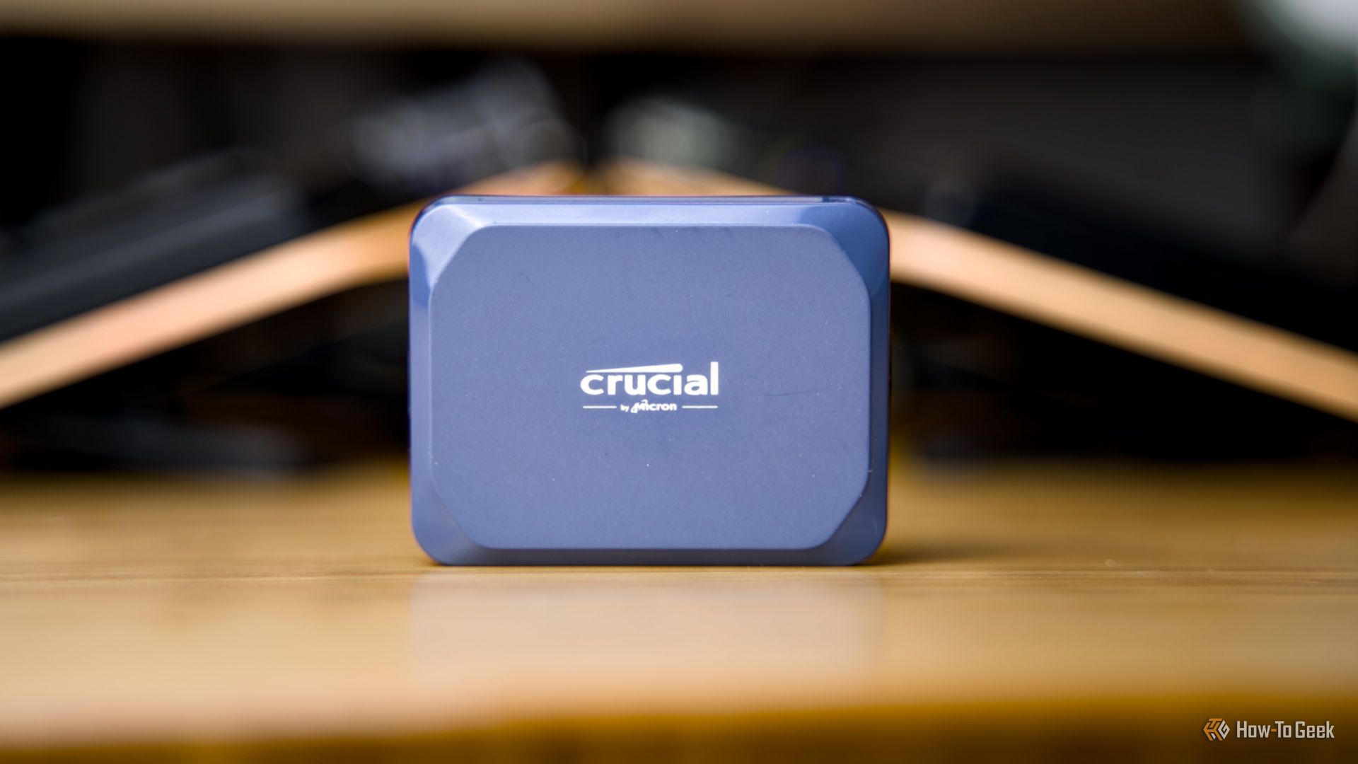 The Crucial X10 portable SSD sitting on a wooden desk.