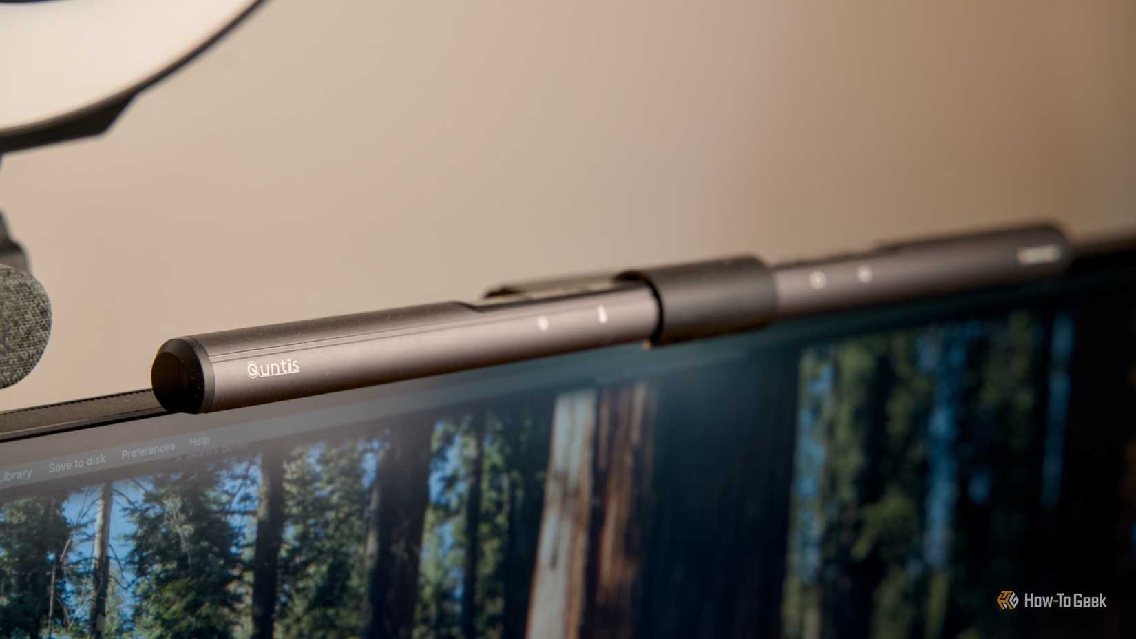 The Quntis ScreenLinear Monitor Light Bar sitting on top of a monitor with a beige wall in the background.