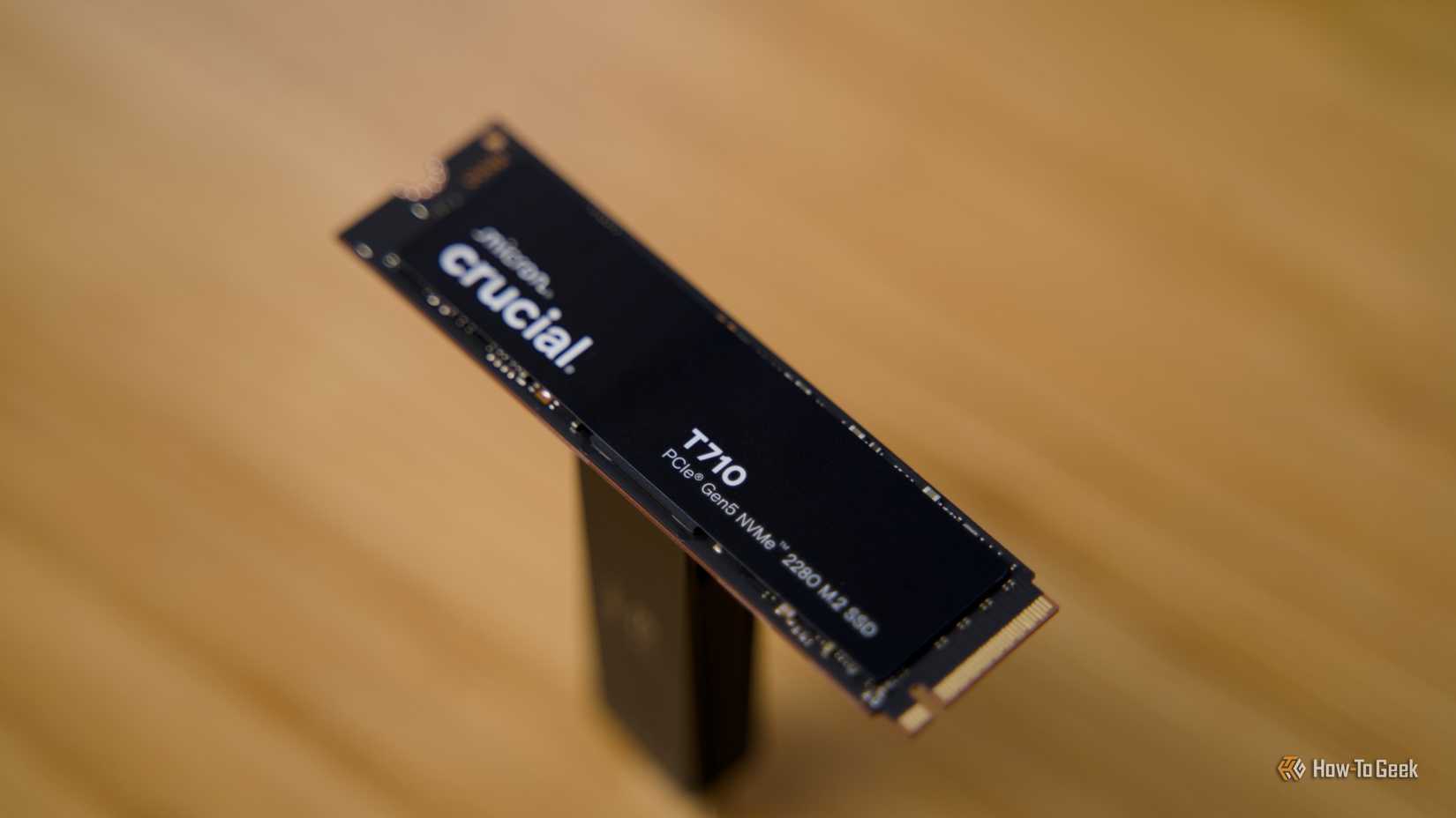 The Crucial T710 NVMe SSD raised off a bamboo desk.