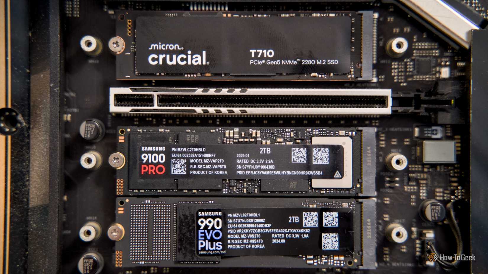 A straight-on shot of the Crucial T710, Samsung 9100 Pro, and Samsung 990 EVO Plus NVMe SSDs mounted to a motherboard.
